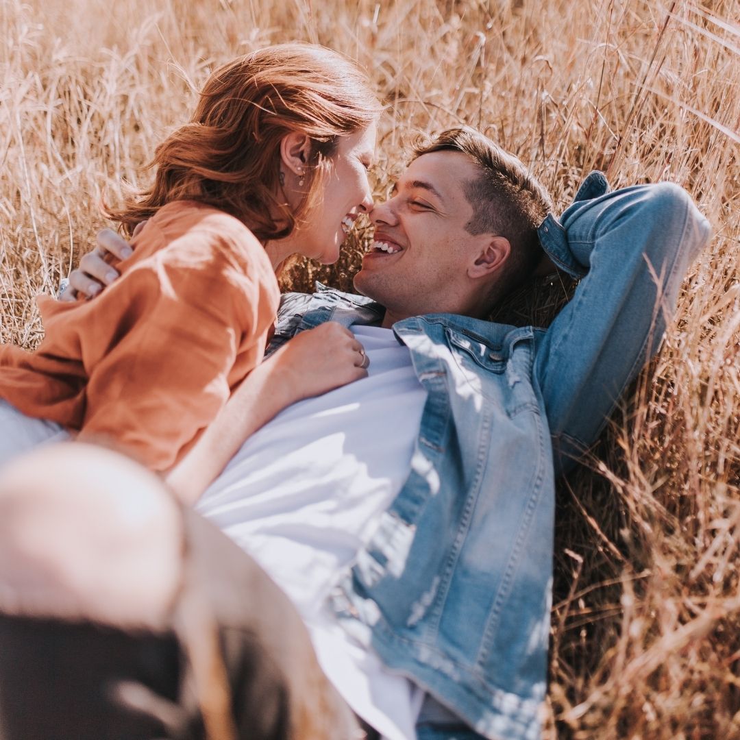 Couple intimately lying in a field