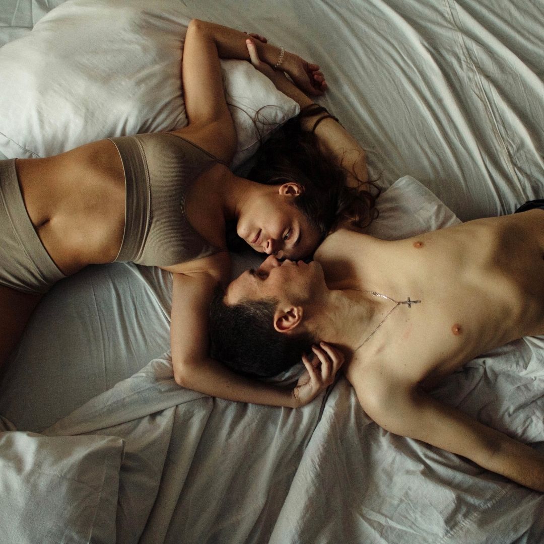 Man and woman in their undergarments lying together in a bed