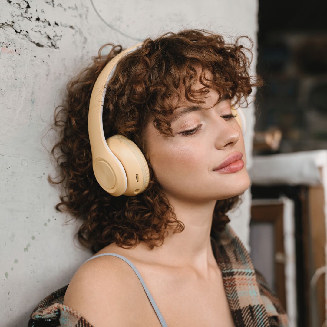 Woman with headphones closing her eyes as she listens